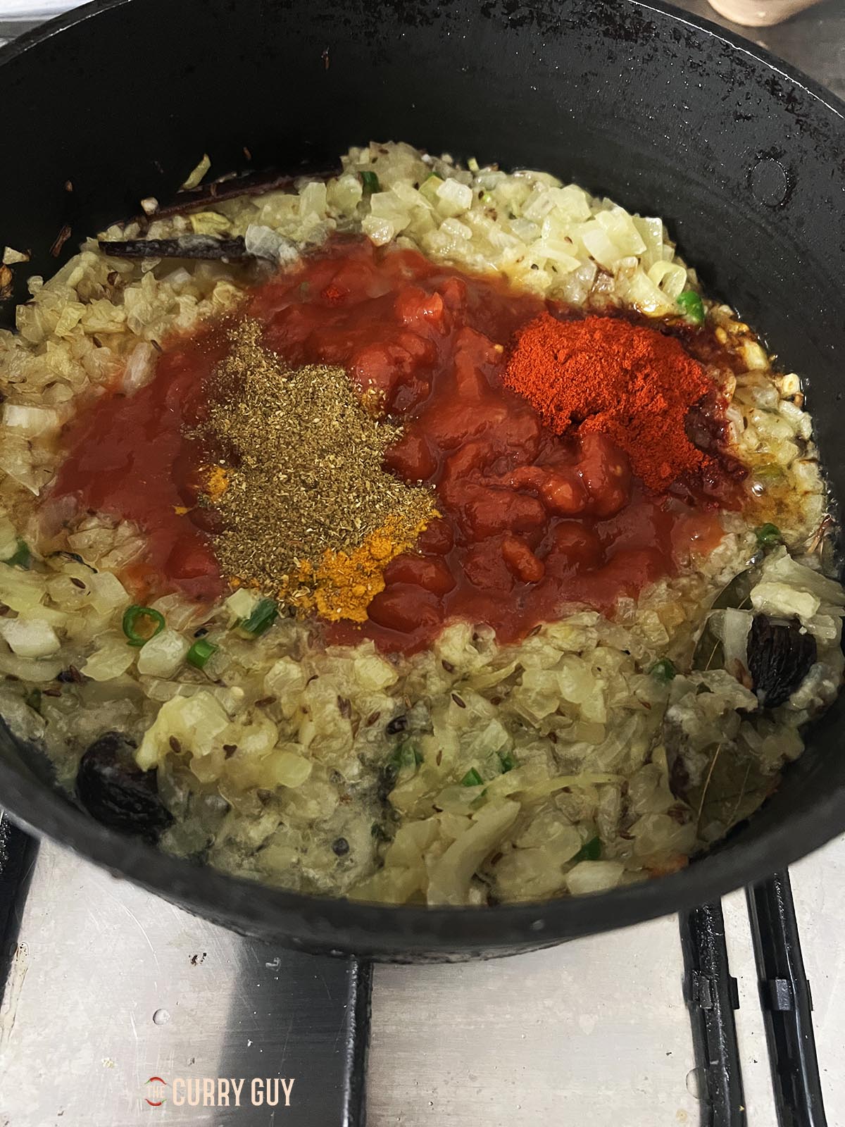 Adding the ground spices and tomatoes to the pan.
