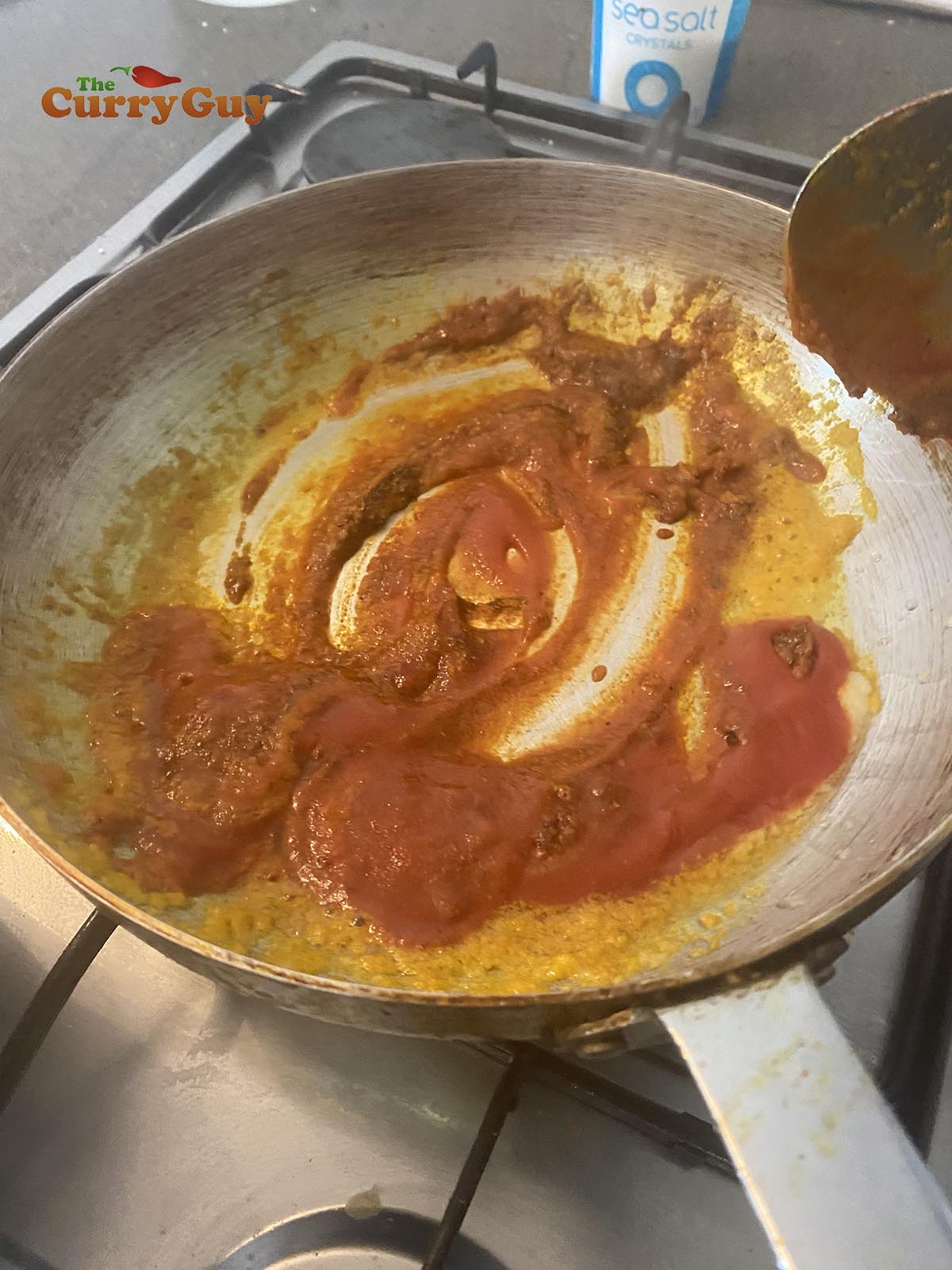 Adding spices and tomato puree to the pan