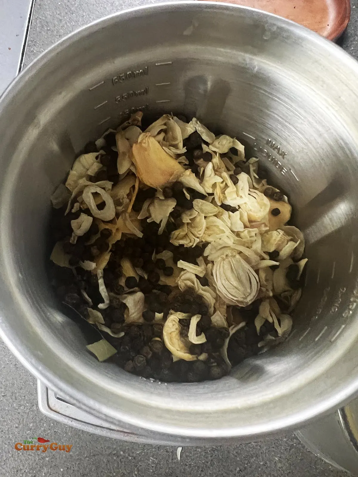 Adding the dried onions and garlic to a spice grinder.