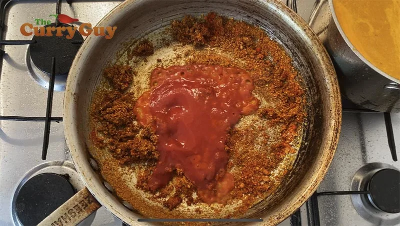 adding tomato puree to sauce