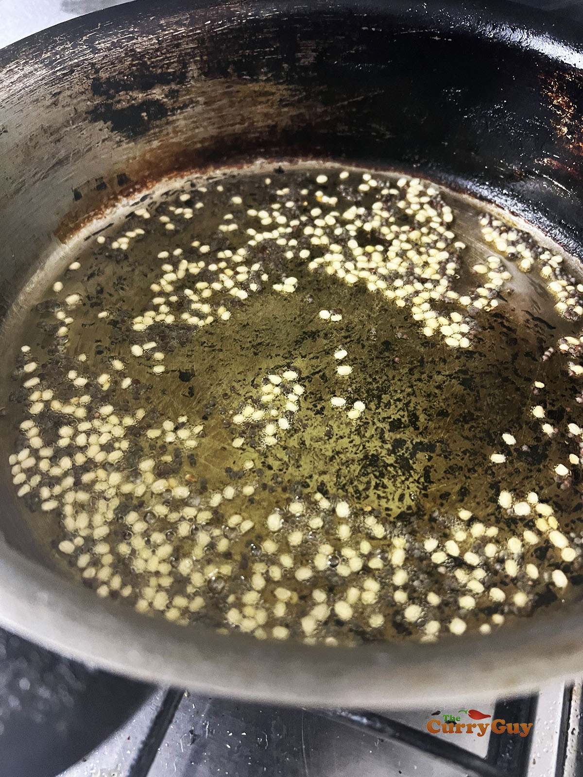 Adding the mustard seeds and lentils to the hot ghee.