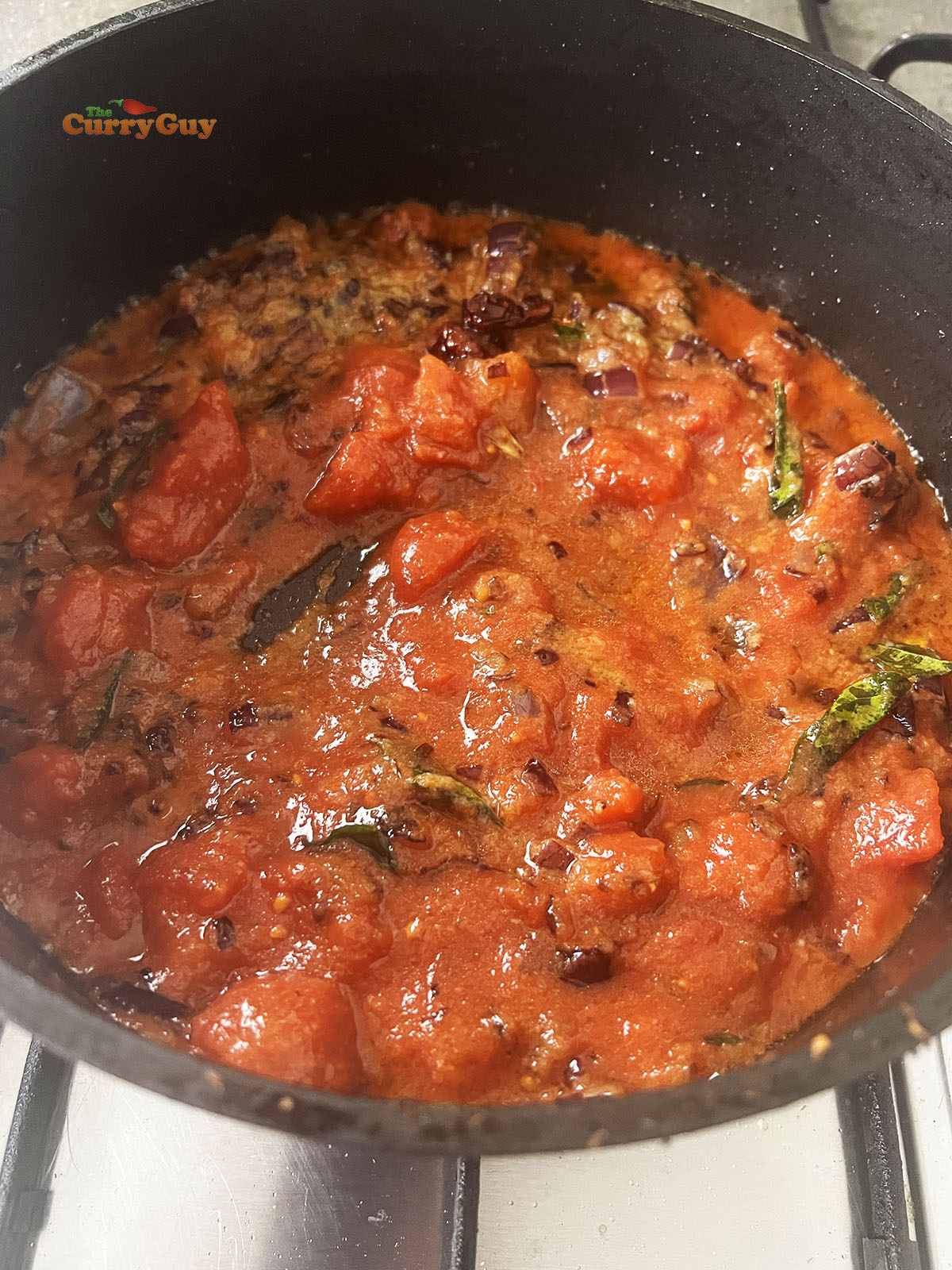 Adding chopped tomatoes to the pan.