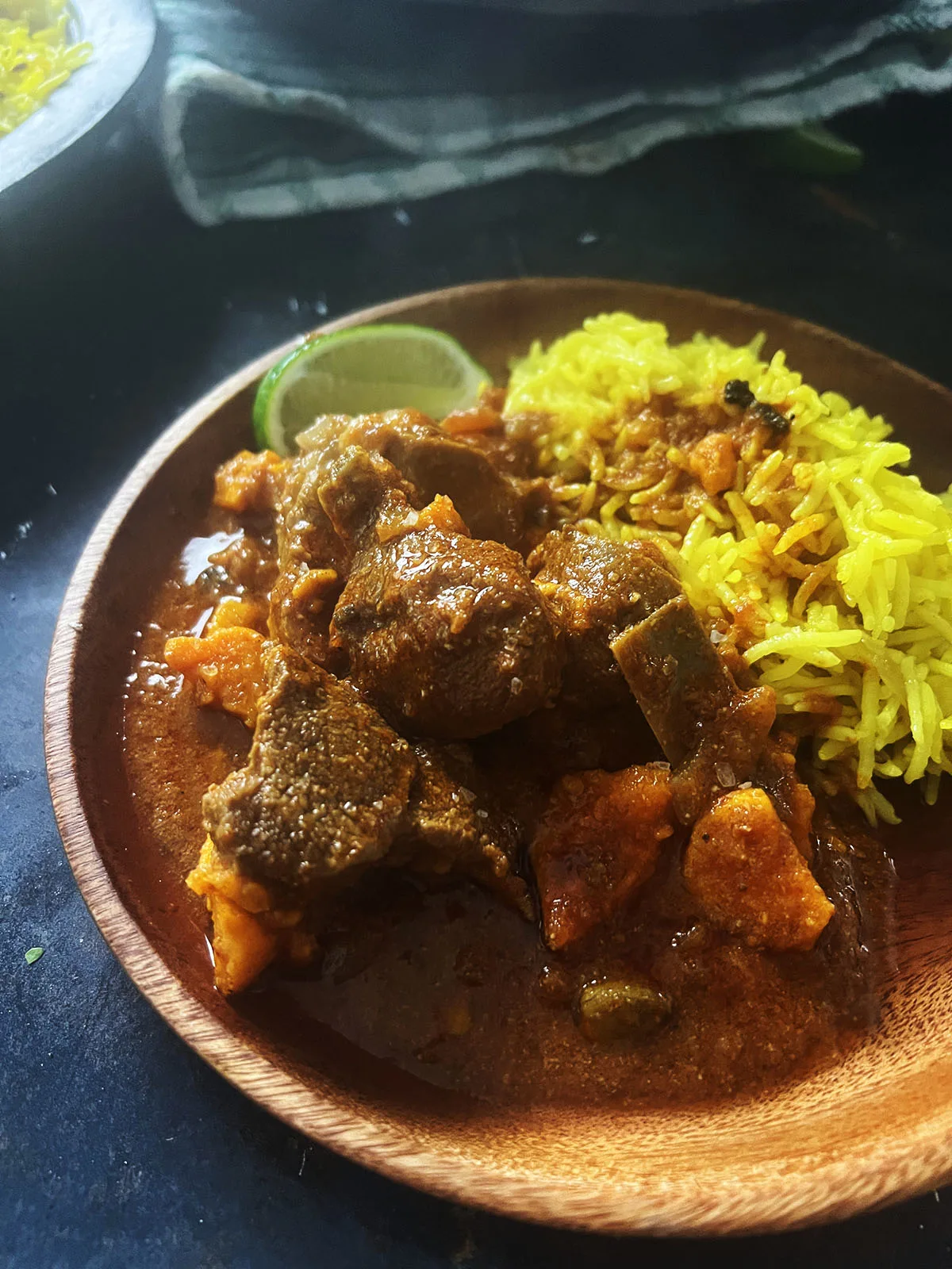 Lamb and sweet potato curry served with rice and lime wedges.