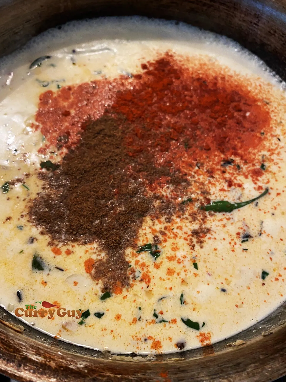 Adding coconut milk and ground spices to pan
