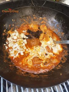 Adding cream, raisons and almonds to curry
