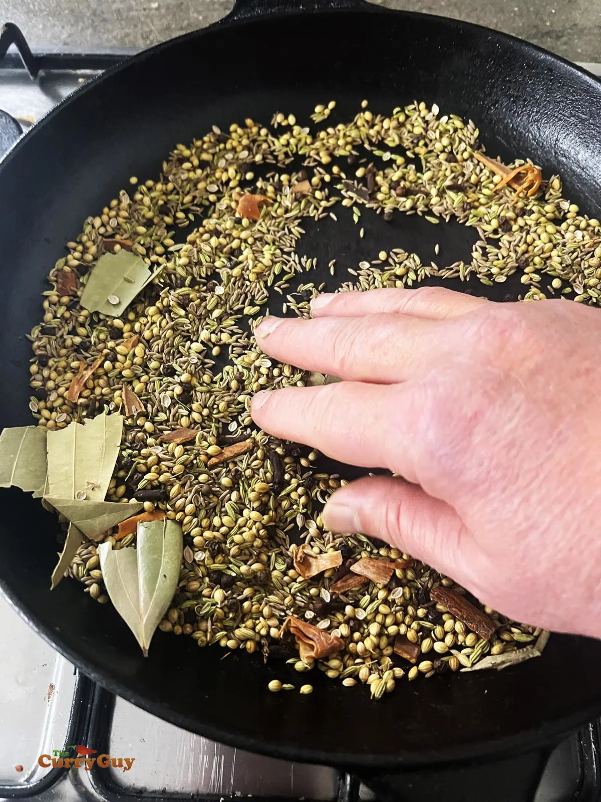 Roasting whole spices in a pan.