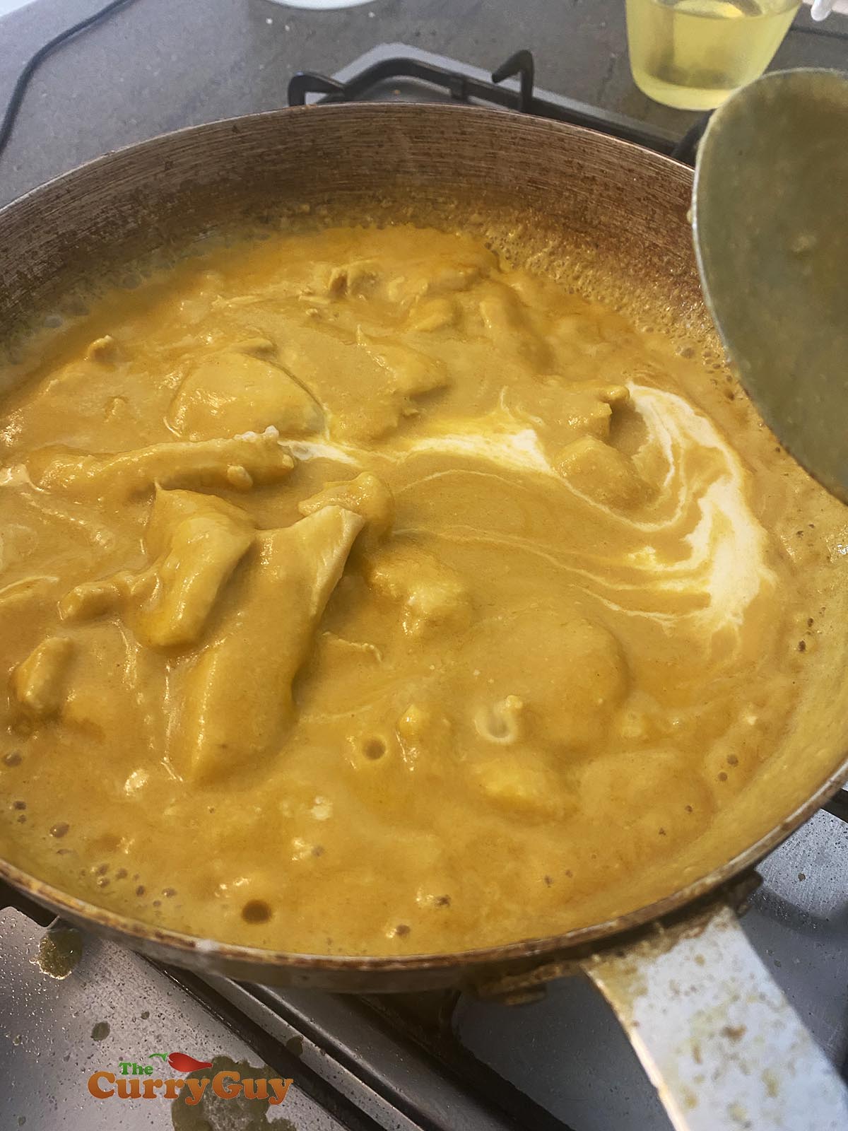 Stirring cream into the chicken korma