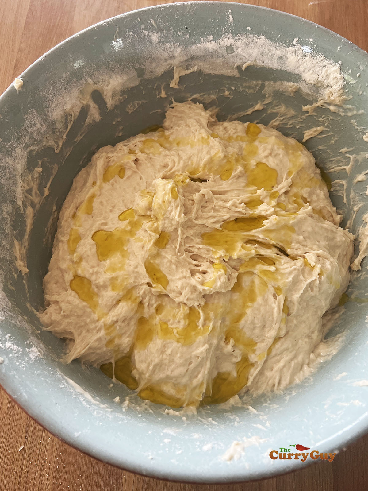 Olive oil drizzled over the dough in a mixing bowl.