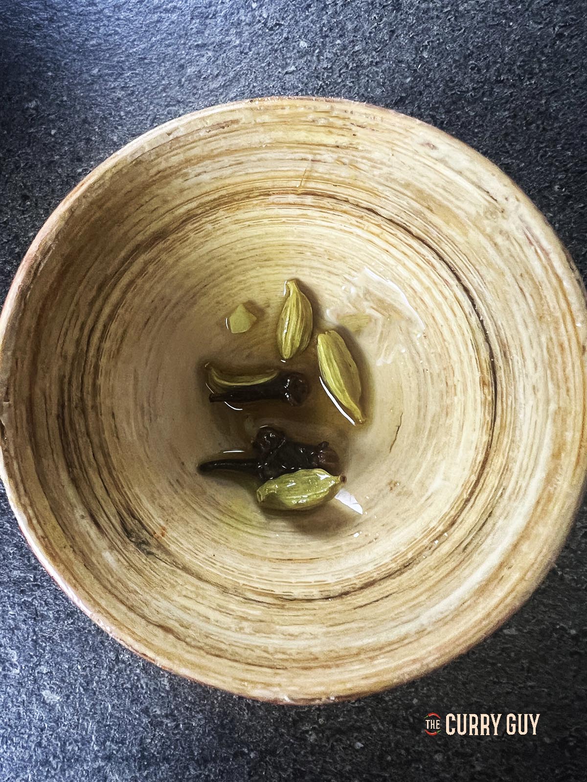 Removing the cardamom pods and cloves from the pan.