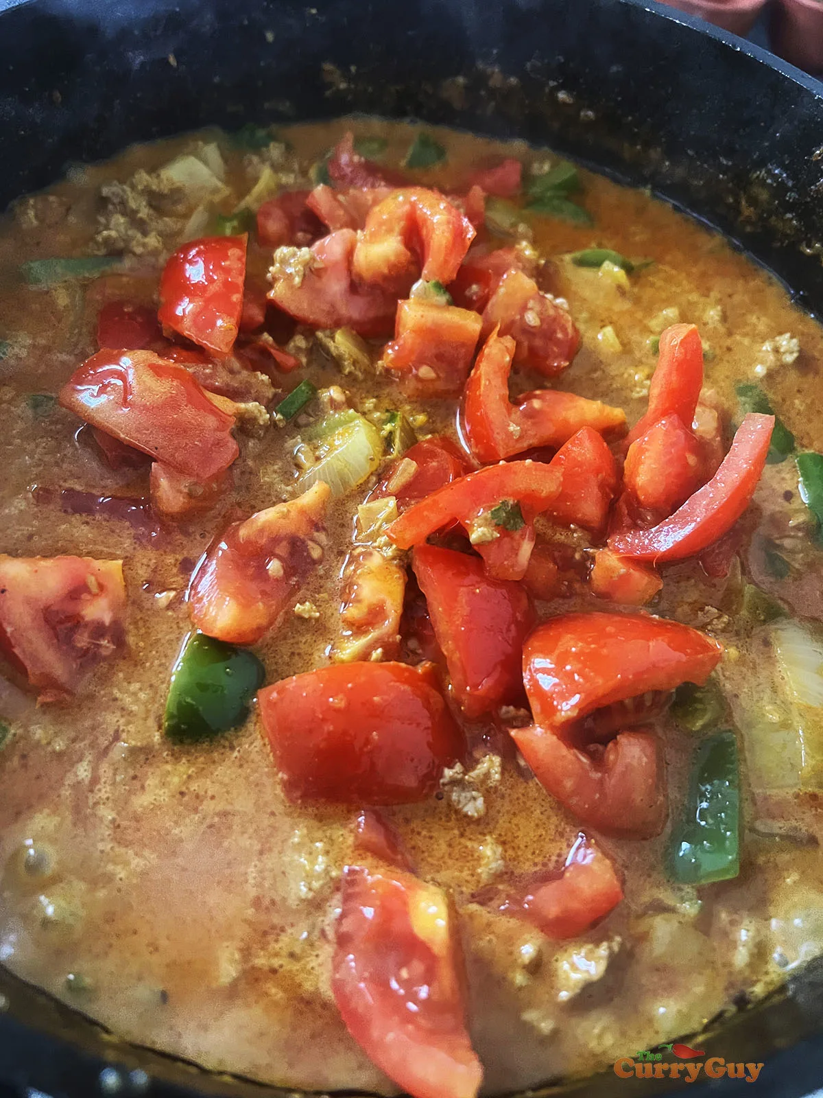 Adding the remaining tomatoes to the shimla mirch curry.