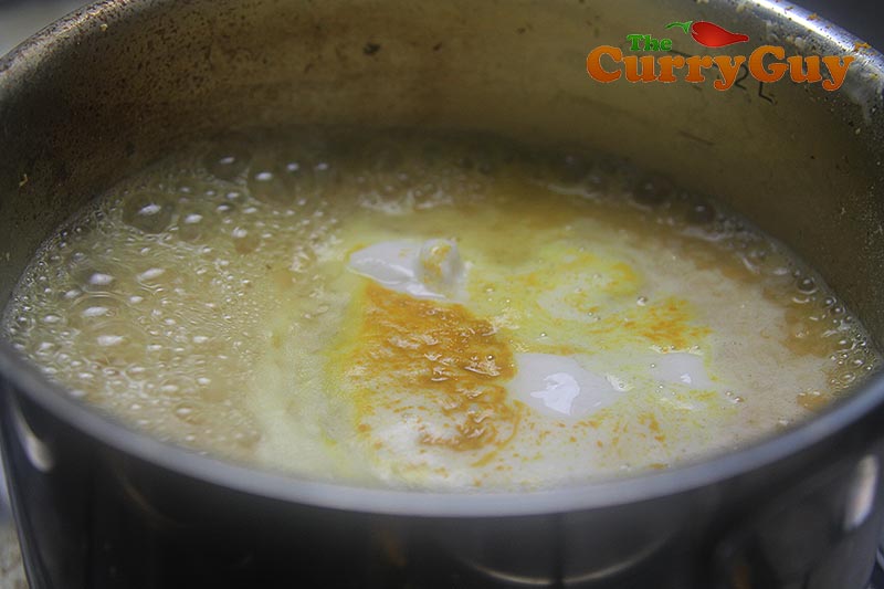 Cooking the masoor dal and adding coconut cream and turmeric.