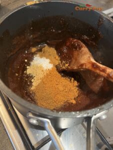 Adding spices and sugar to tamarind concentrate.