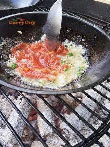 Adding ground spices and tomato puree to pan