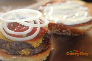 Adding onions to a burger.