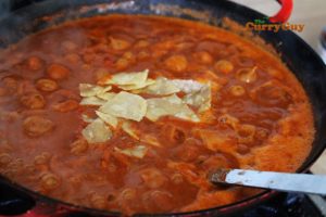 Adding handful of corn chips to sauce
