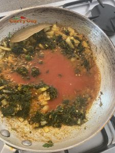 Adding tomato puree to pan.