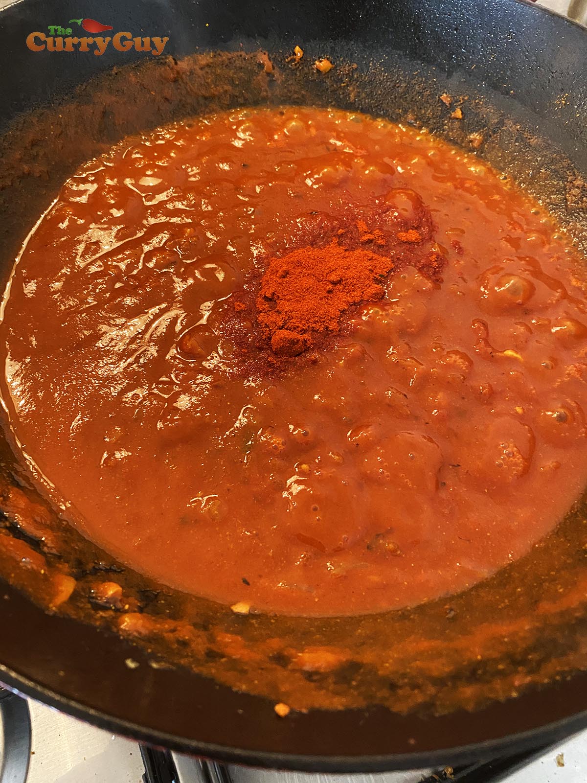 Adding tomatoes and water to sauce.