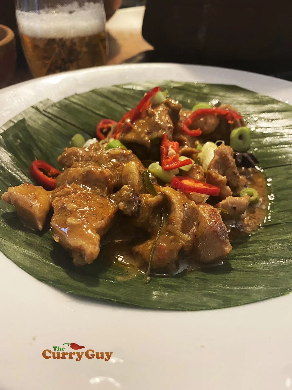 Rendang curry with chicken presented on a banana leaf.