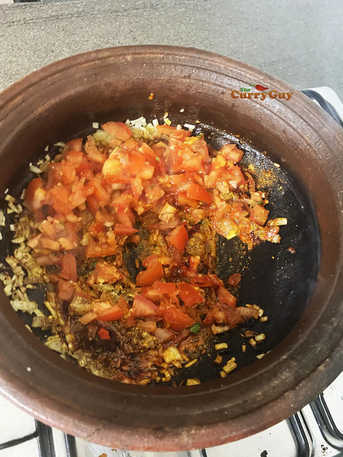 Adding garlic, ginger and tomatoes to pot. 