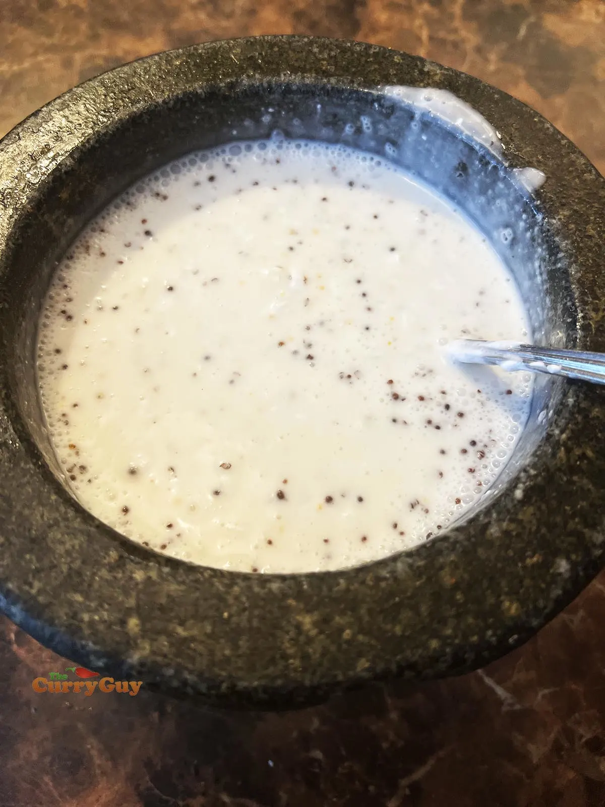 Adding coconut milk to pestle and mortar ingredients