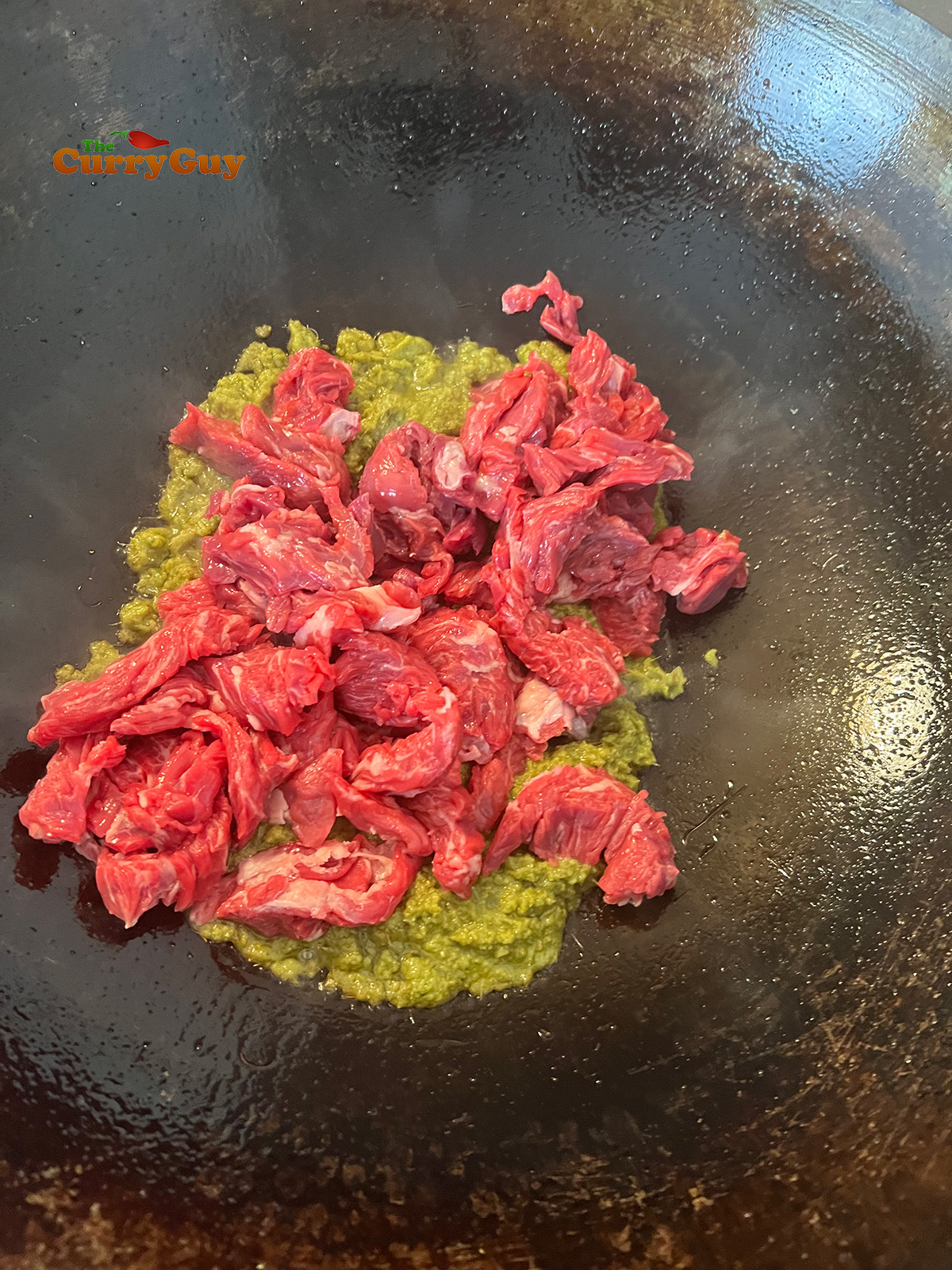 Adding beef to curry paste in wok