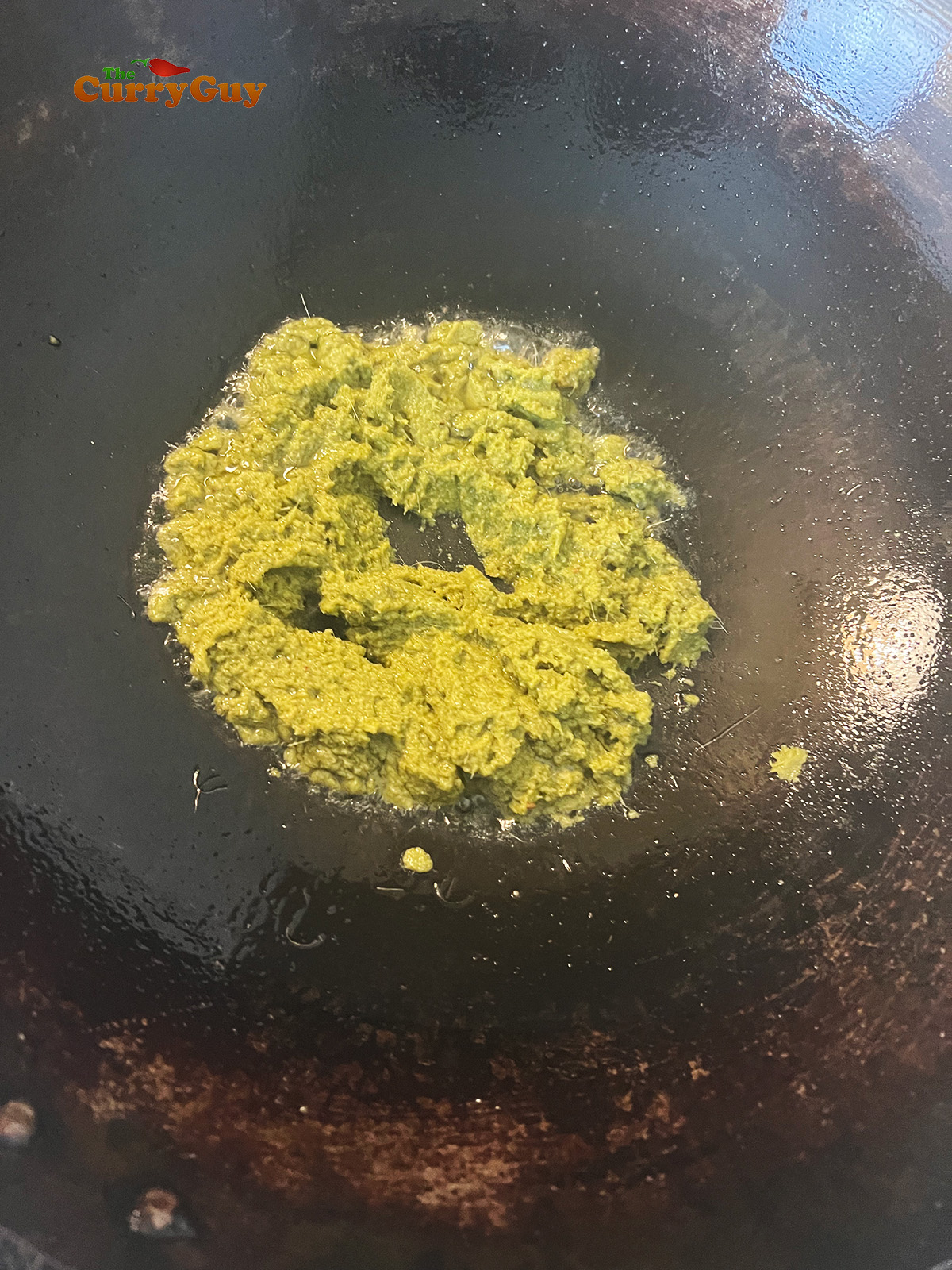 Adding green curry paste to wok