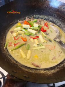 Adding vegetables to green curry