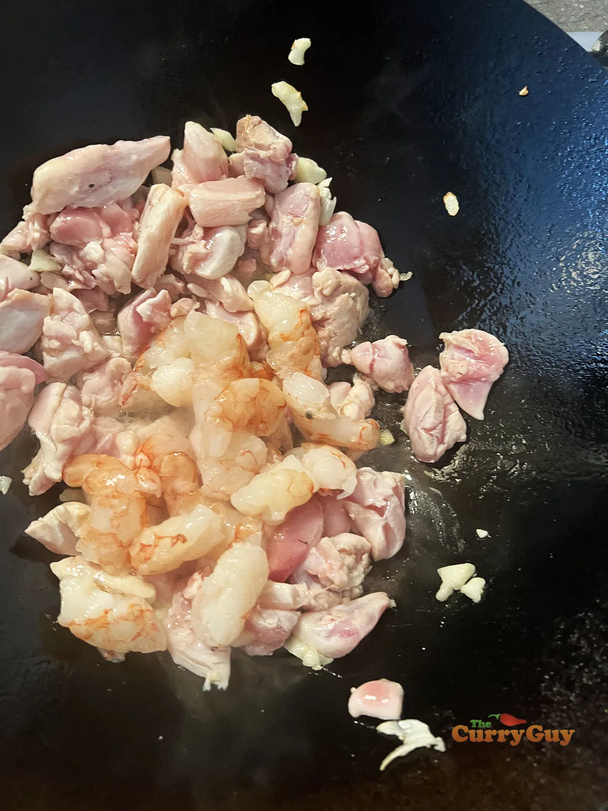 Adding chicken and prawns to the wok