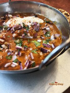 Garnishing the curry with coriander (cilantro) and red onion