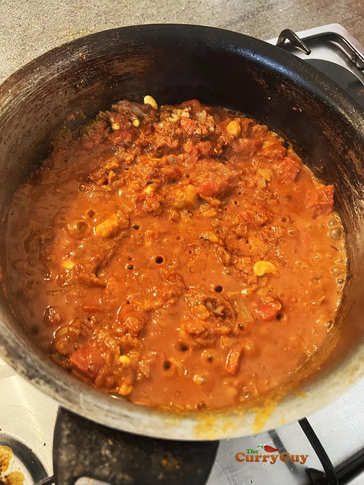 Adding chopped tomatoes and stock to the pan