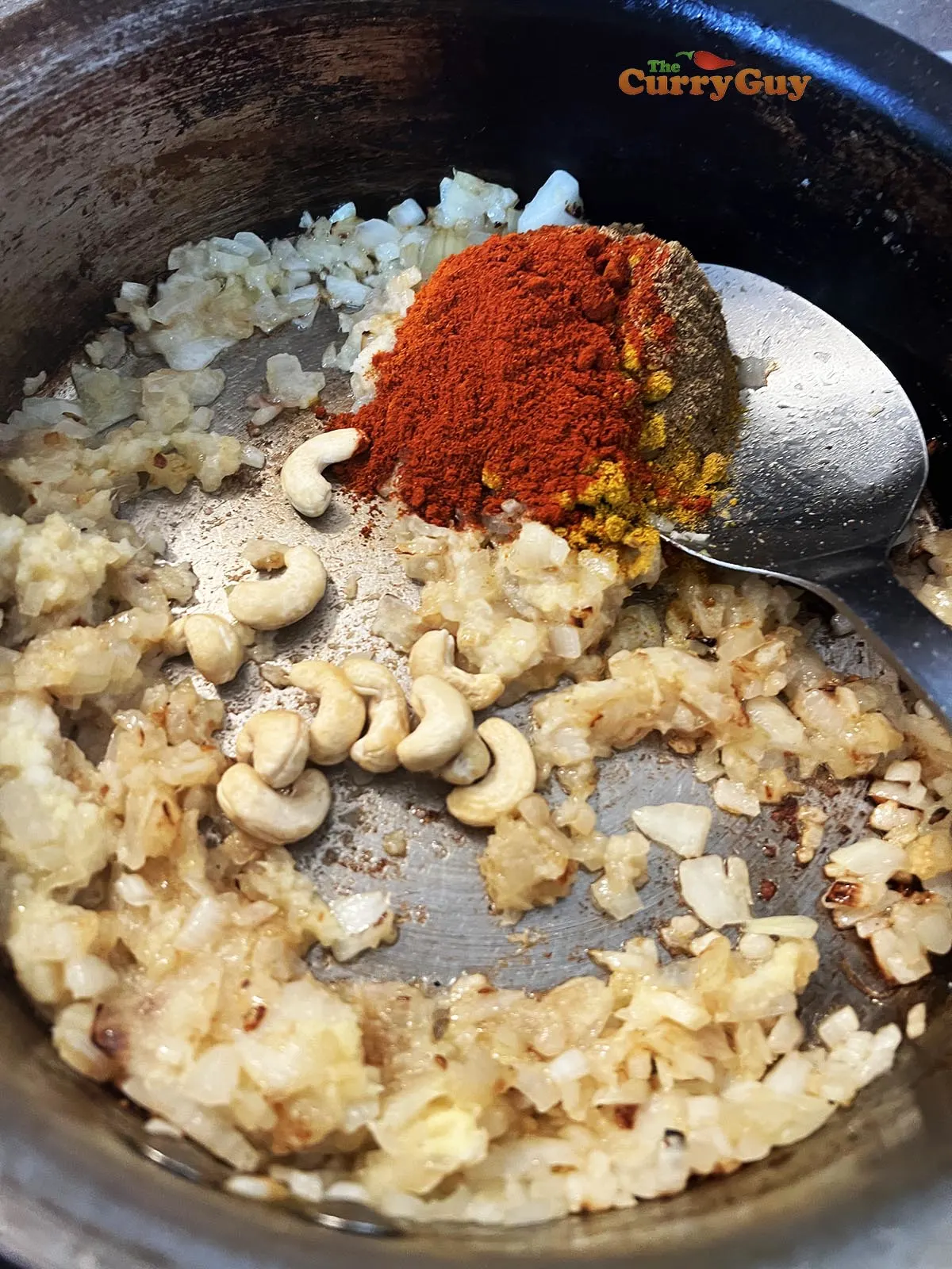 Adding garlic and ginger, spices and cashews