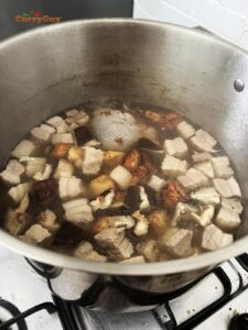 Adding tofu and mushrooms to the stock in the pan