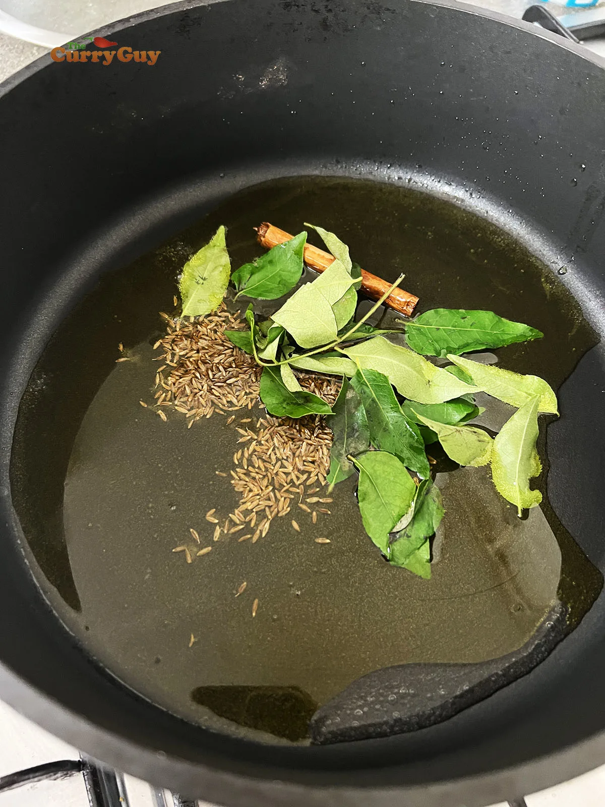 Infusing the curry leaves, cumin seeds and cinnamon stick in the hot ghee