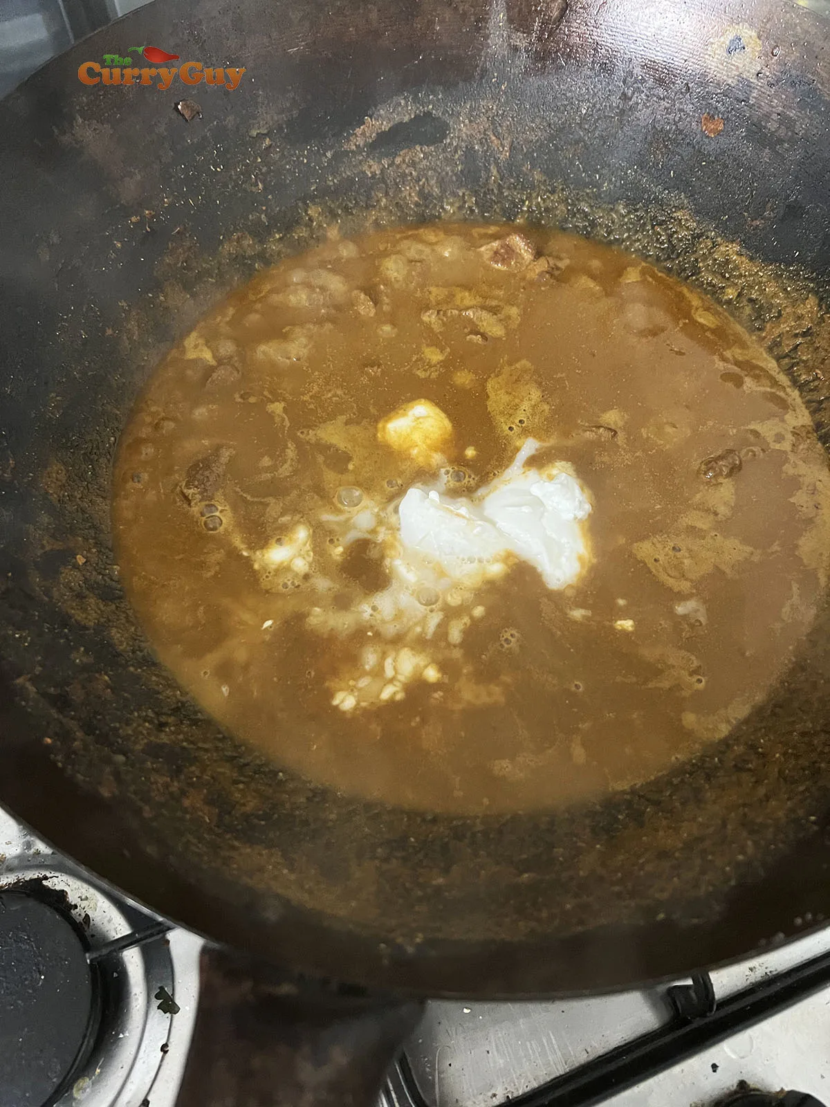 Simmering beef with stock and coconut milk