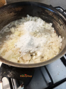 Adding coconut, almonds and sugar to frying onions.