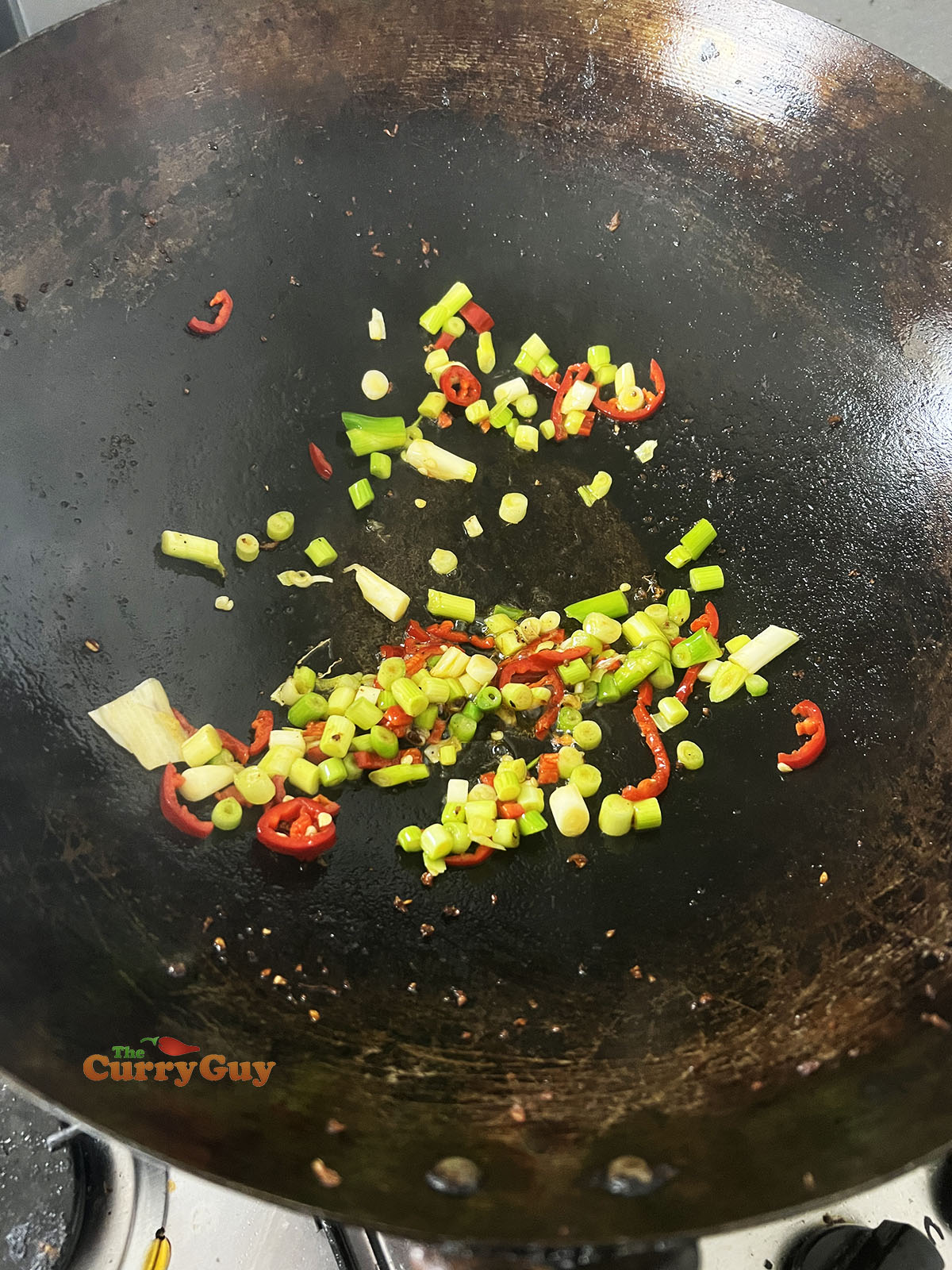Frying spring onions (scallions) and chillies