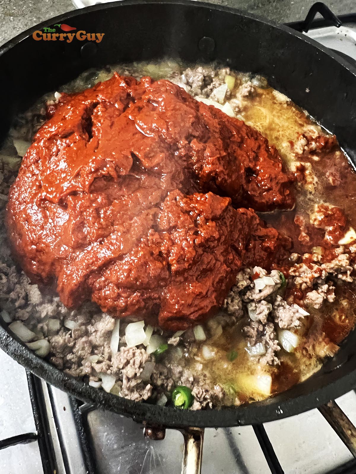 Adding the blended chili paste to the pan.