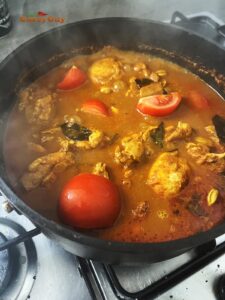 Simmering the kari ayam stock and adding tomatoes.