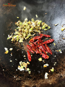Adding dried whole chilies to the wok