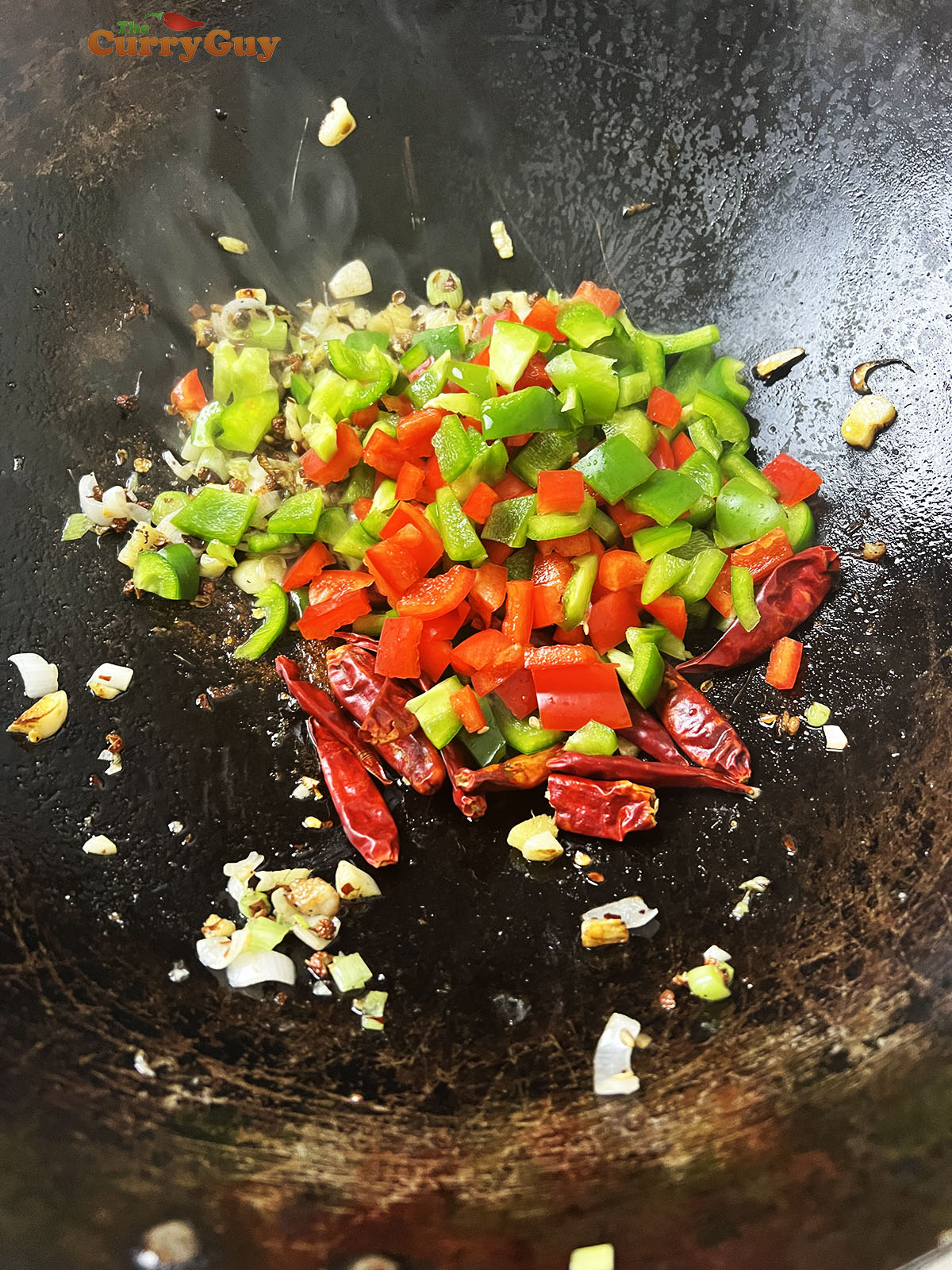 Adding diced bell peppers to the wok