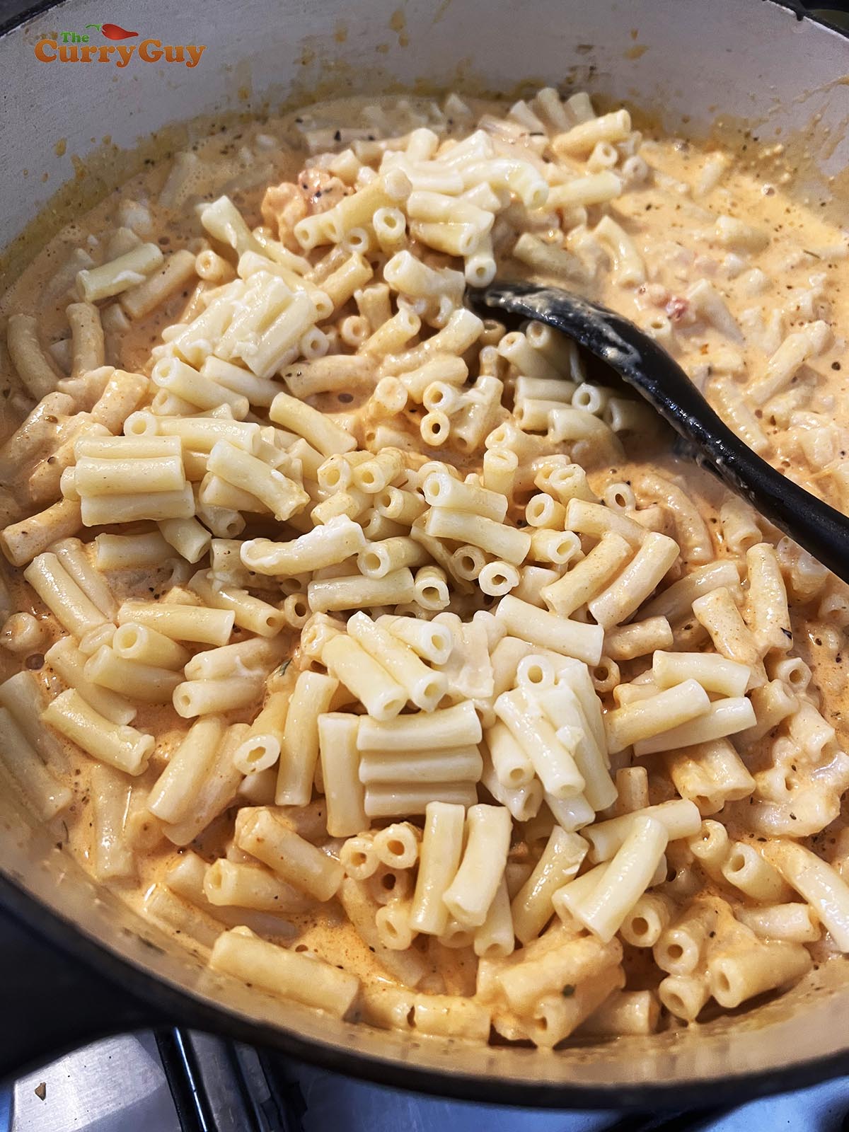 Stirring macaroni into sauce.