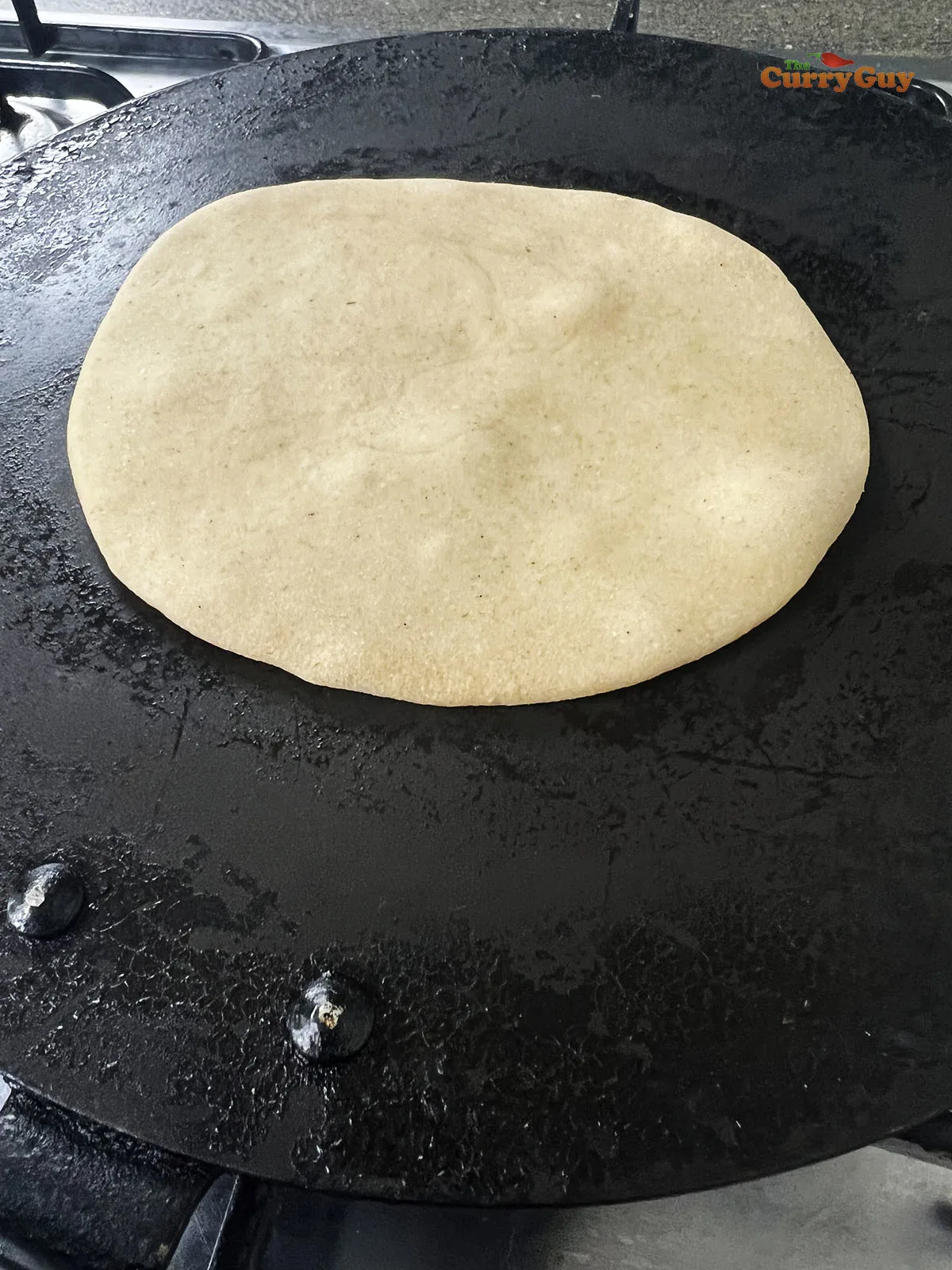 Chapati cooking with bubbles forming.