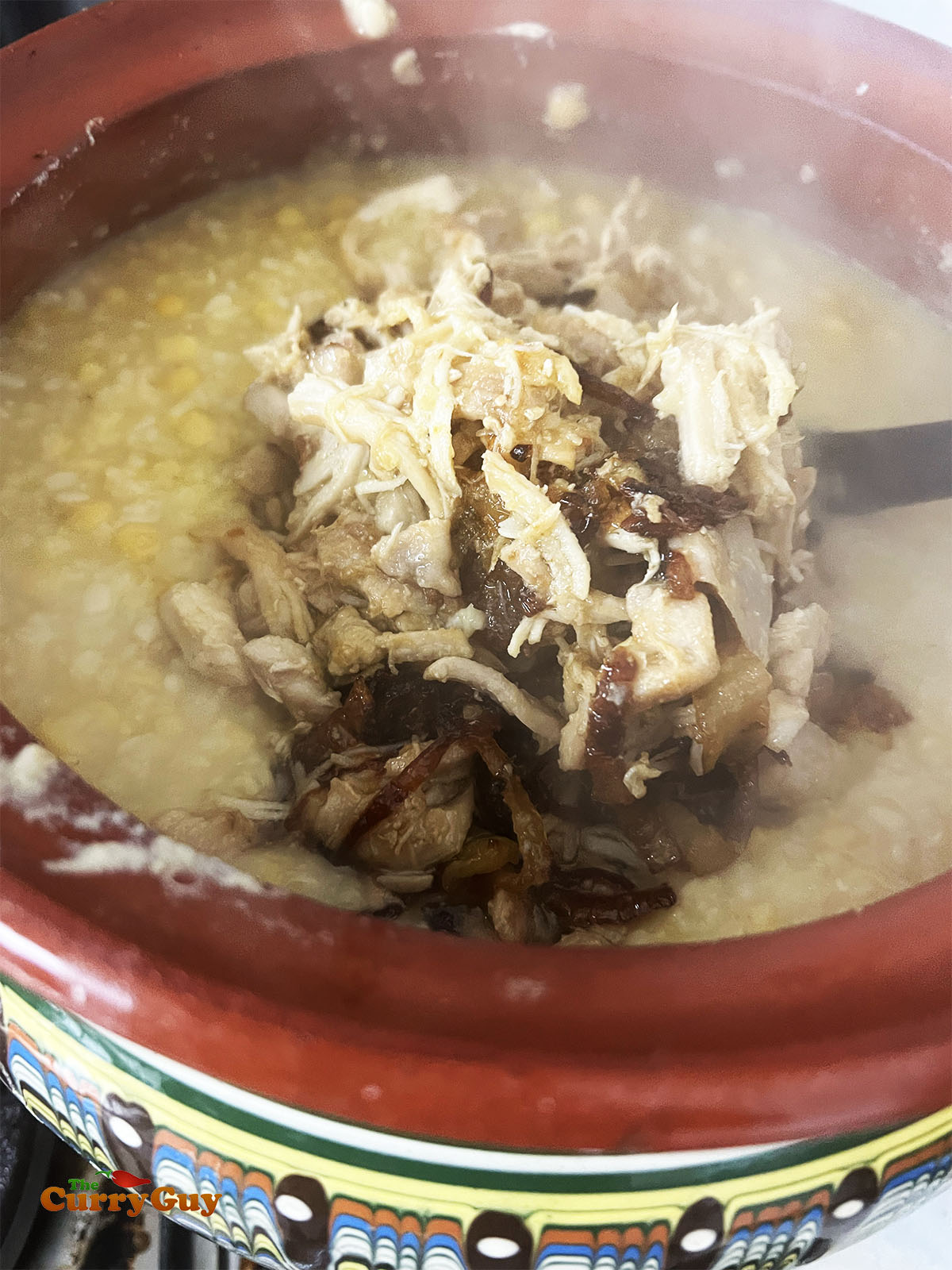 Adding the shredded chicken, fried onions and ghee to the pot.