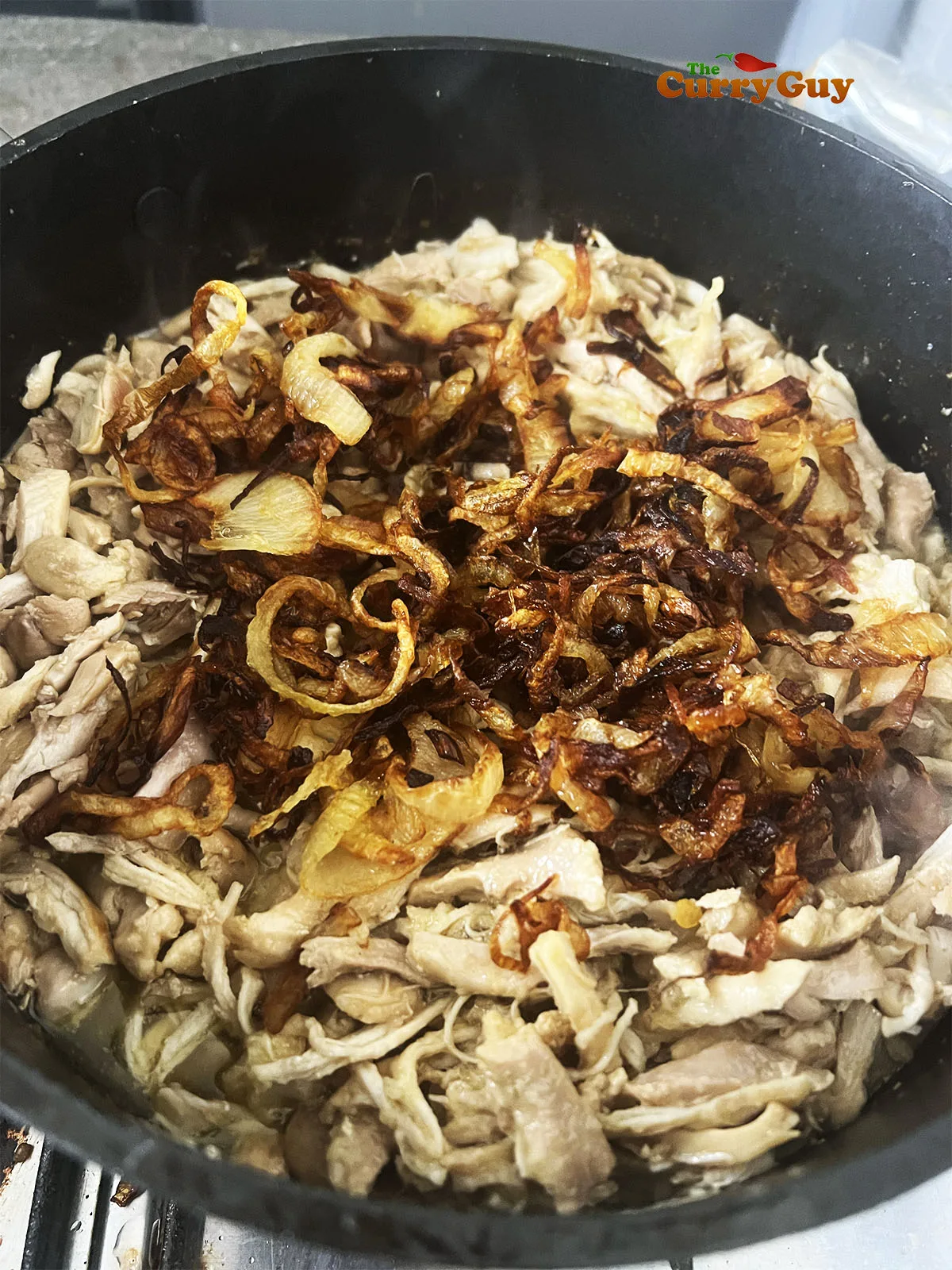 Chicken and fried onions in the pan with the ghee.