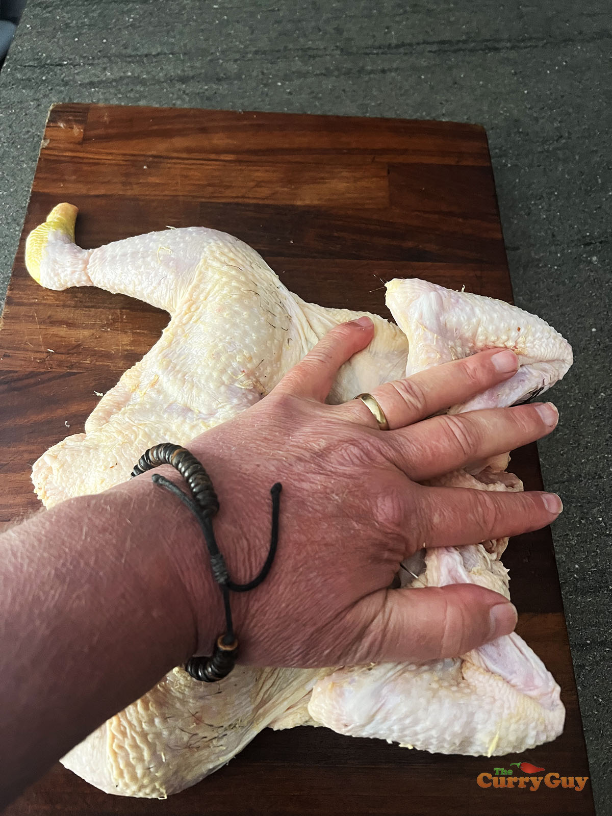 Pushing the spatchcock chicken down to flatten it.