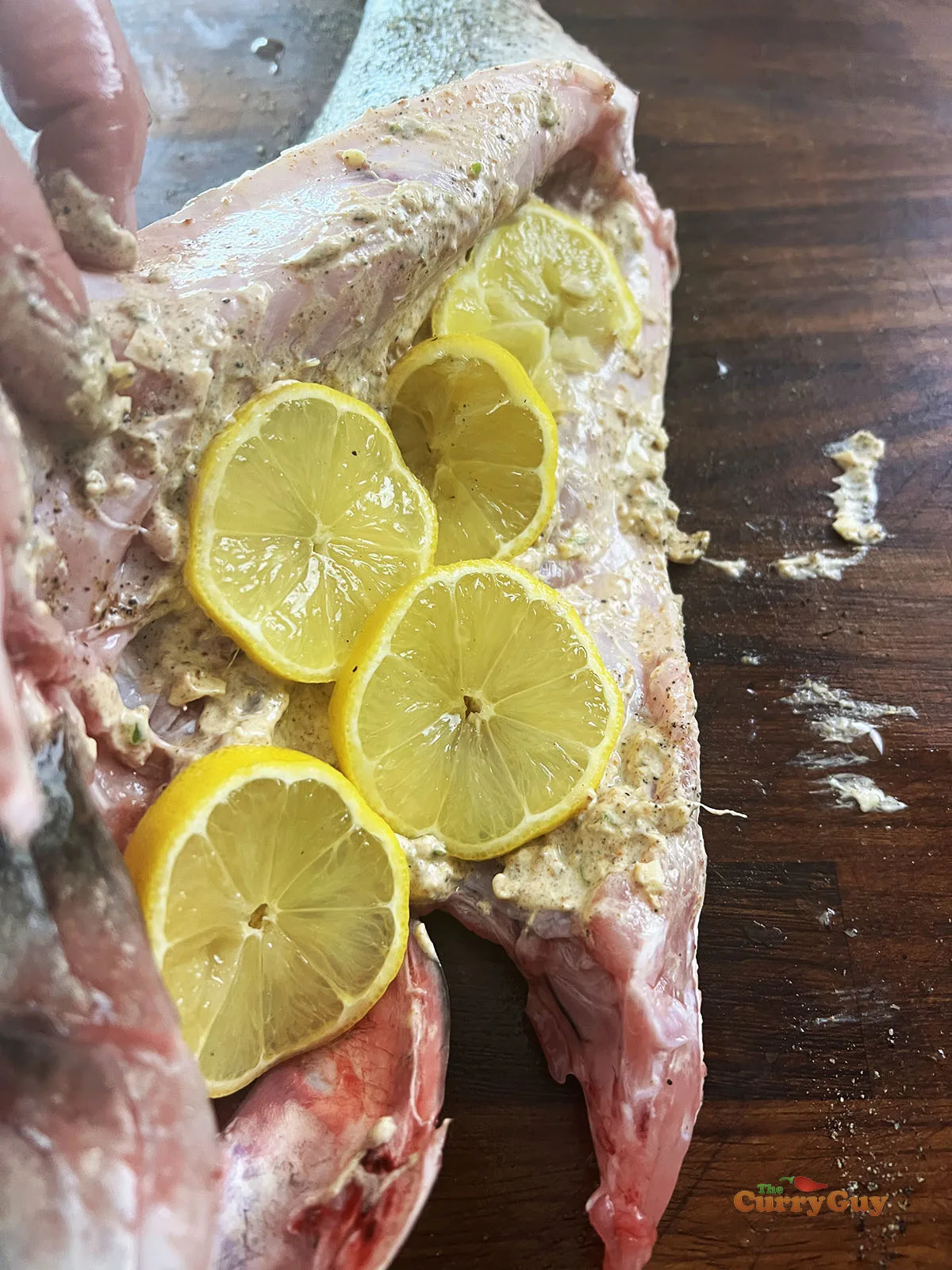 Inside cavity of the fish seasoned with salt and pepper and the marinade and sliced lemons.