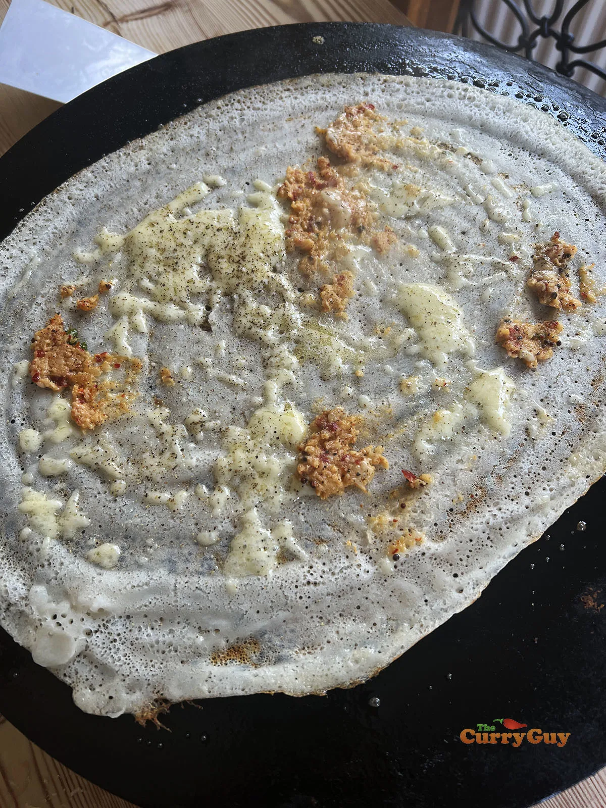 Adding cheese and garlic chutney to the dosa.