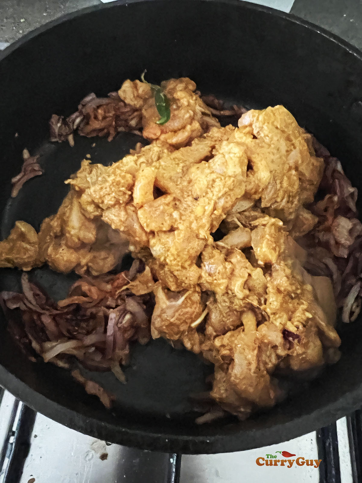 Adding the marinated chicken and chillies to the pan.
