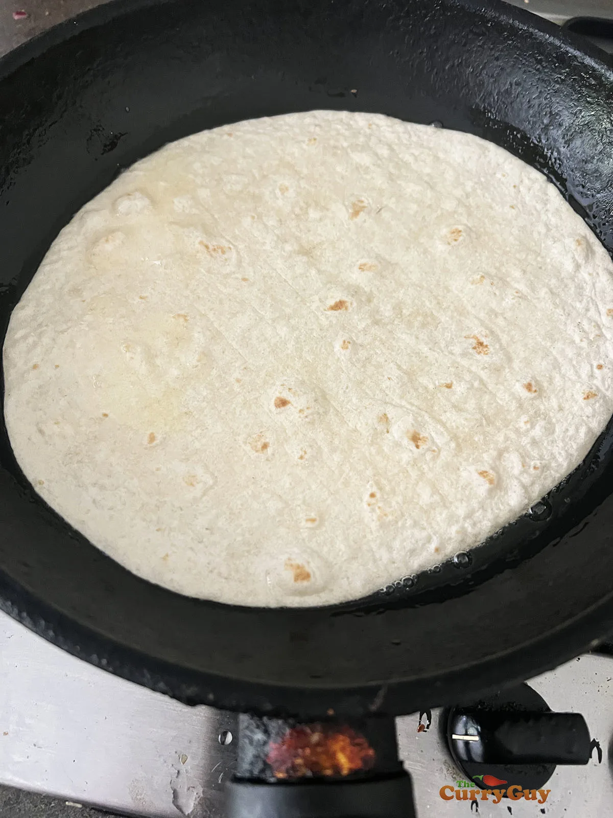 Adding tortilla to oil in a pan.