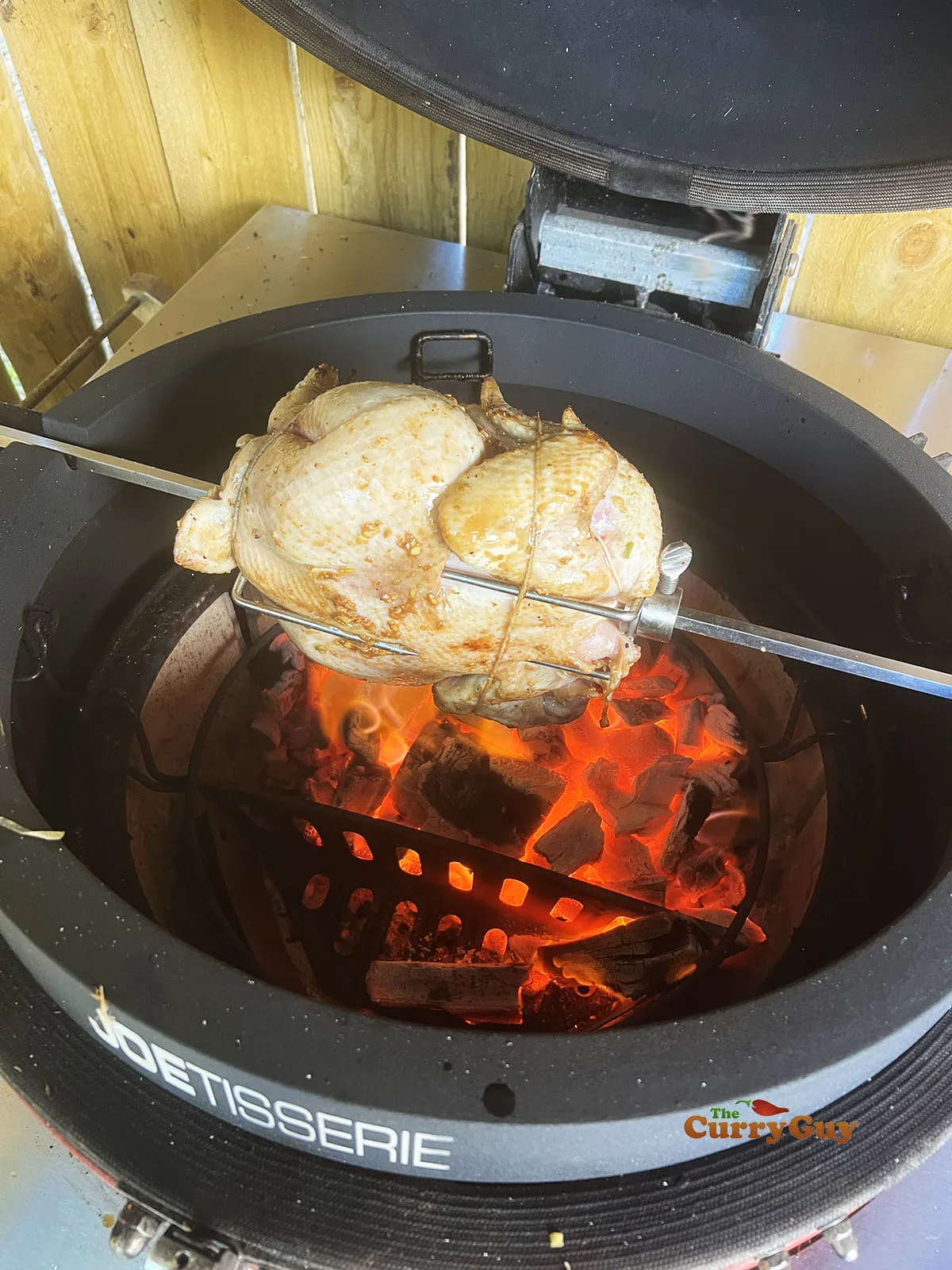 Placing the chicken over the barbecue on the rotisserie.